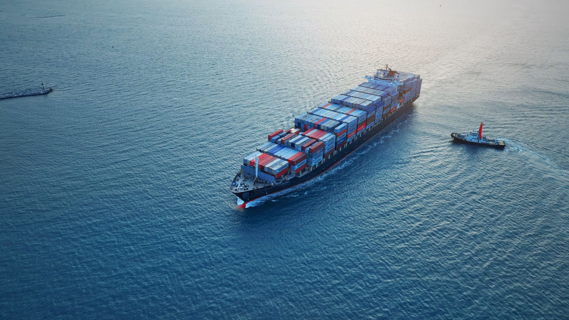 Container Shipping to Kauai 2 A large cargo ship loaded with containers sailing on calm waters.