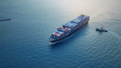 A large container ship, sails across calm ocean waters.